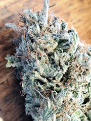 Close-up of a cannabis bud with trichomes on a wooden surface