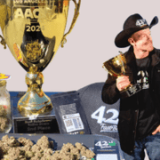 James 'Chubbsks' Ziegler holding trophies with blue 420 Fast Buds packets in background