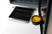 Close-up of a cure machine with a black container holding yellow sponge on a white background