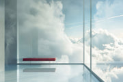 Red bench inside a glass box with a view of clouds outside