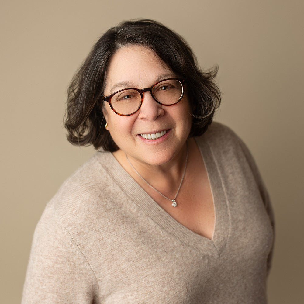 Jane Sandelman wearing glasses and a beige sweater against a beige background