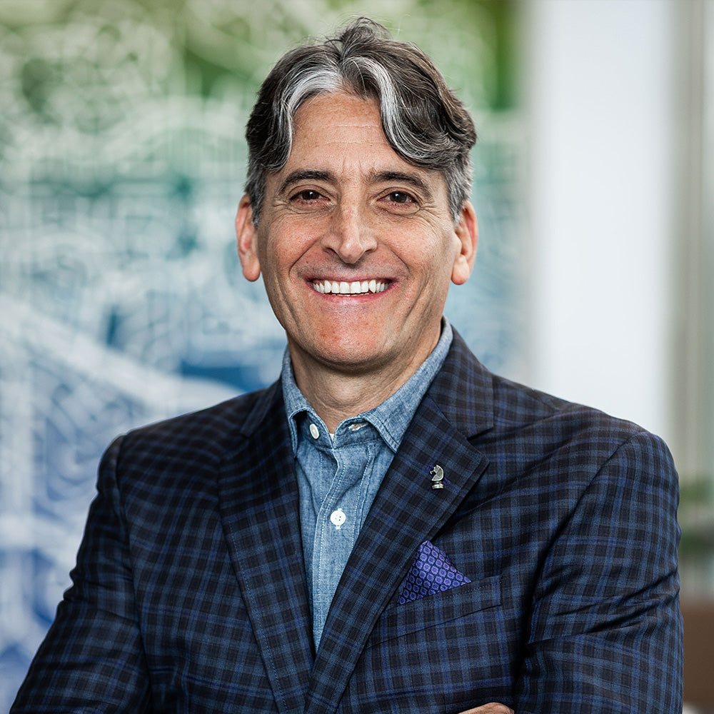 Michael Lucchino in a checkered suit with a blurred background